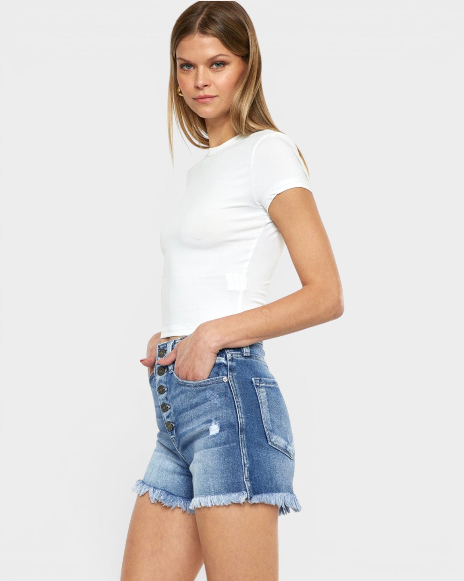 Woman wearing a white t-shirt and denim shorts on a plain background