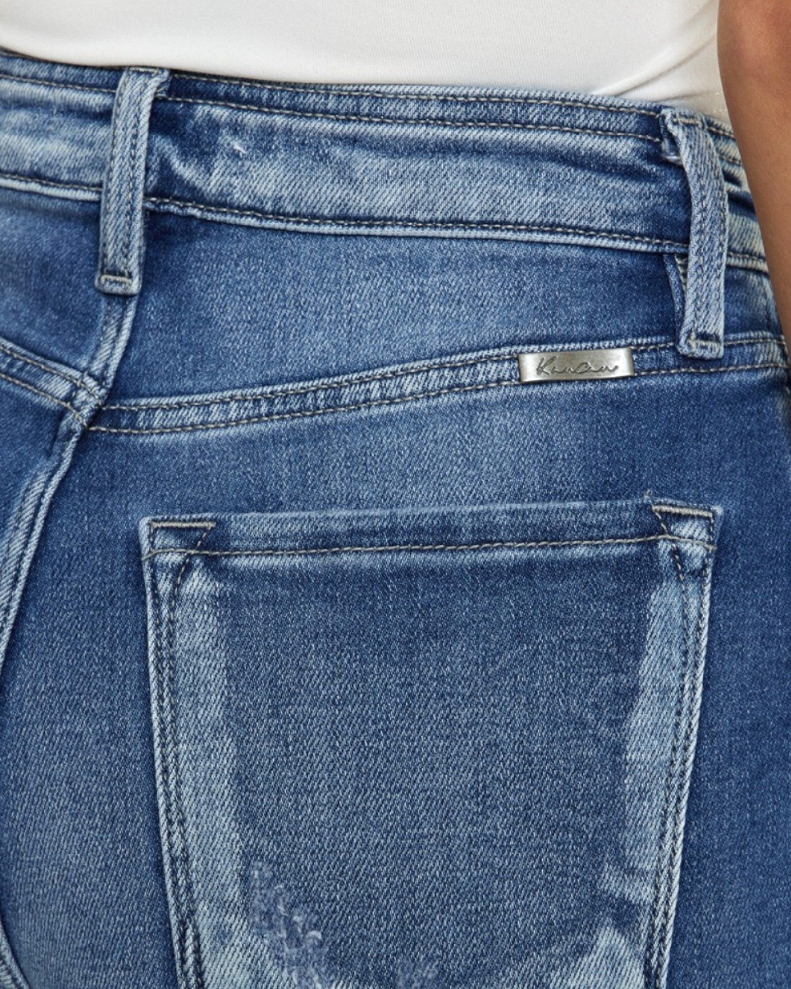 Close-up of blue jeans with a brand label on the back pocket.