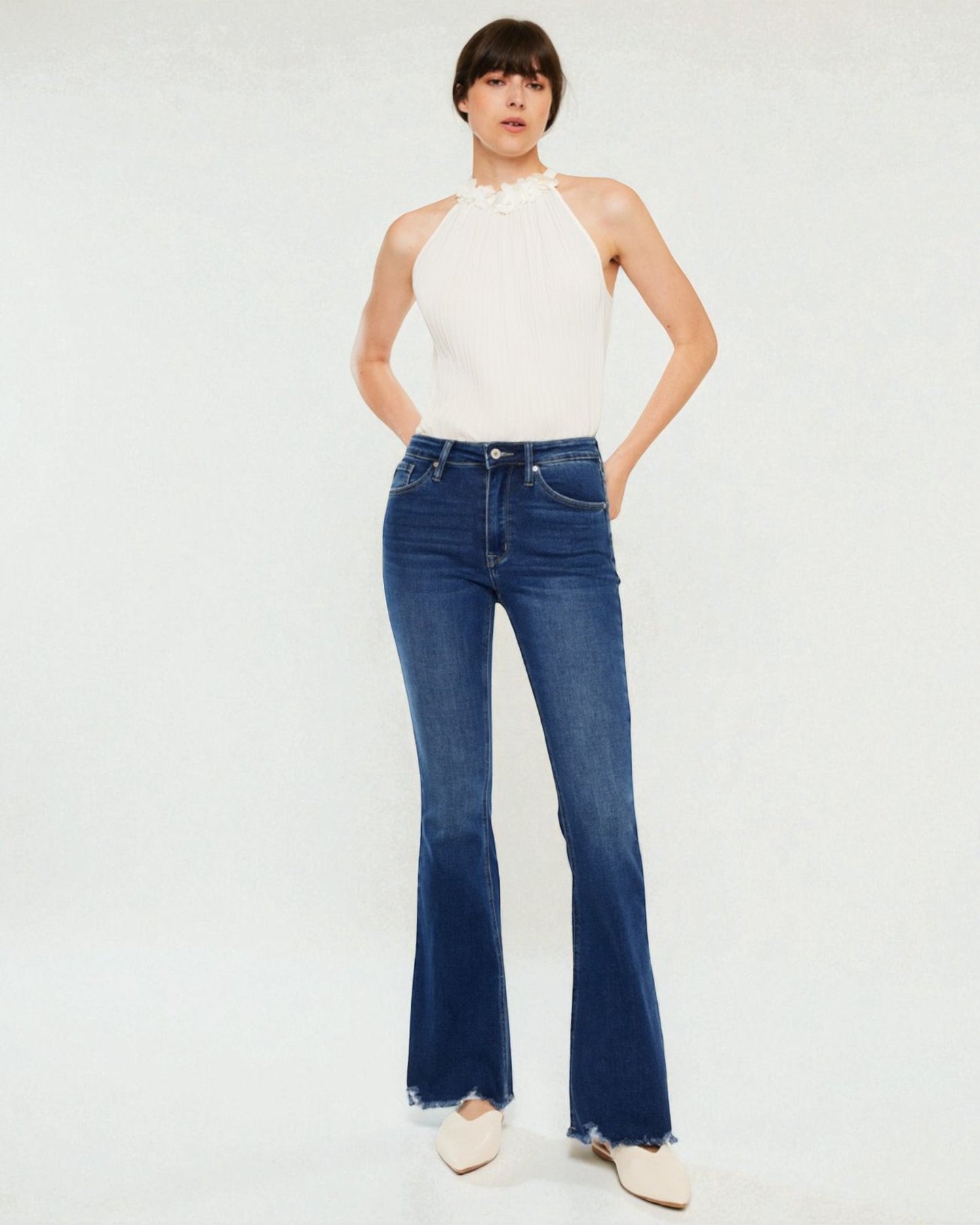 Woman wearing blue jeans and a white top on a white background