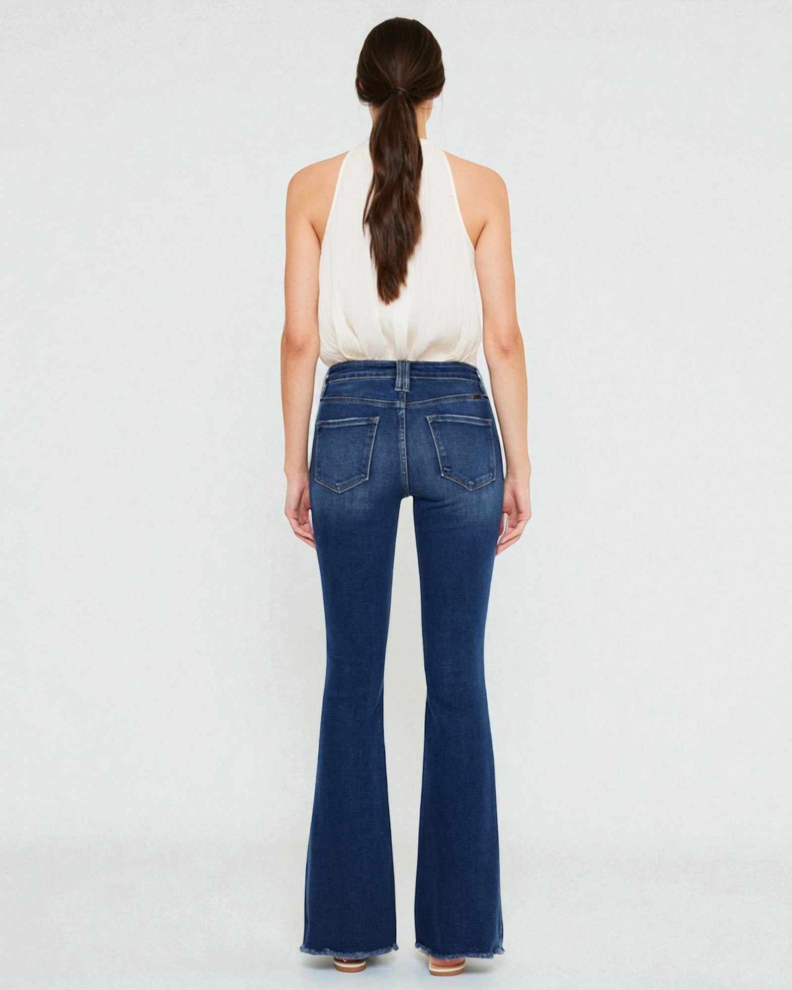 Person wearing blue flared jeans on a white background