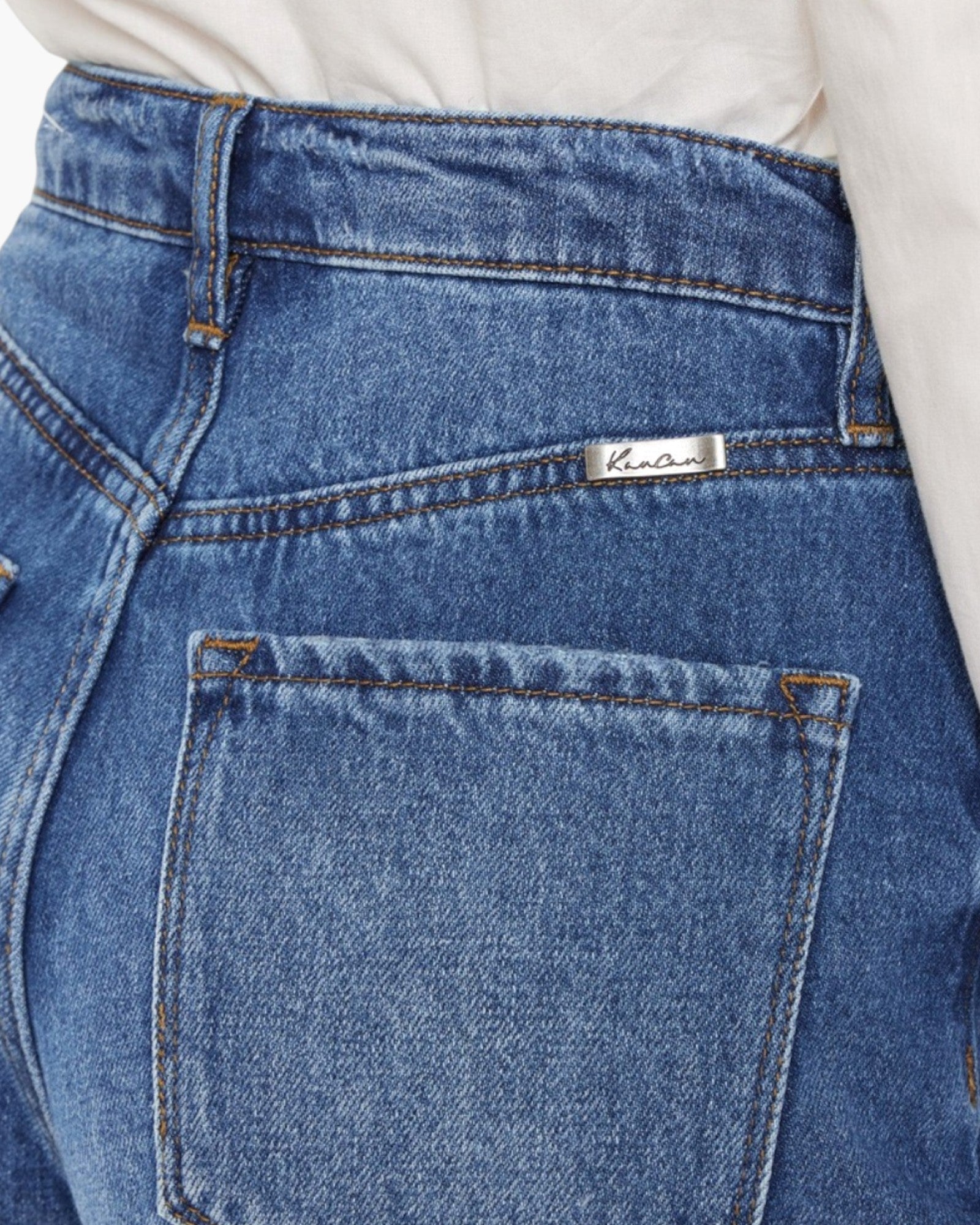 Close-up of the back waistband and pocket area of blue denim jeans, with a small white brand label reading 'kano' visible near the back pocket.