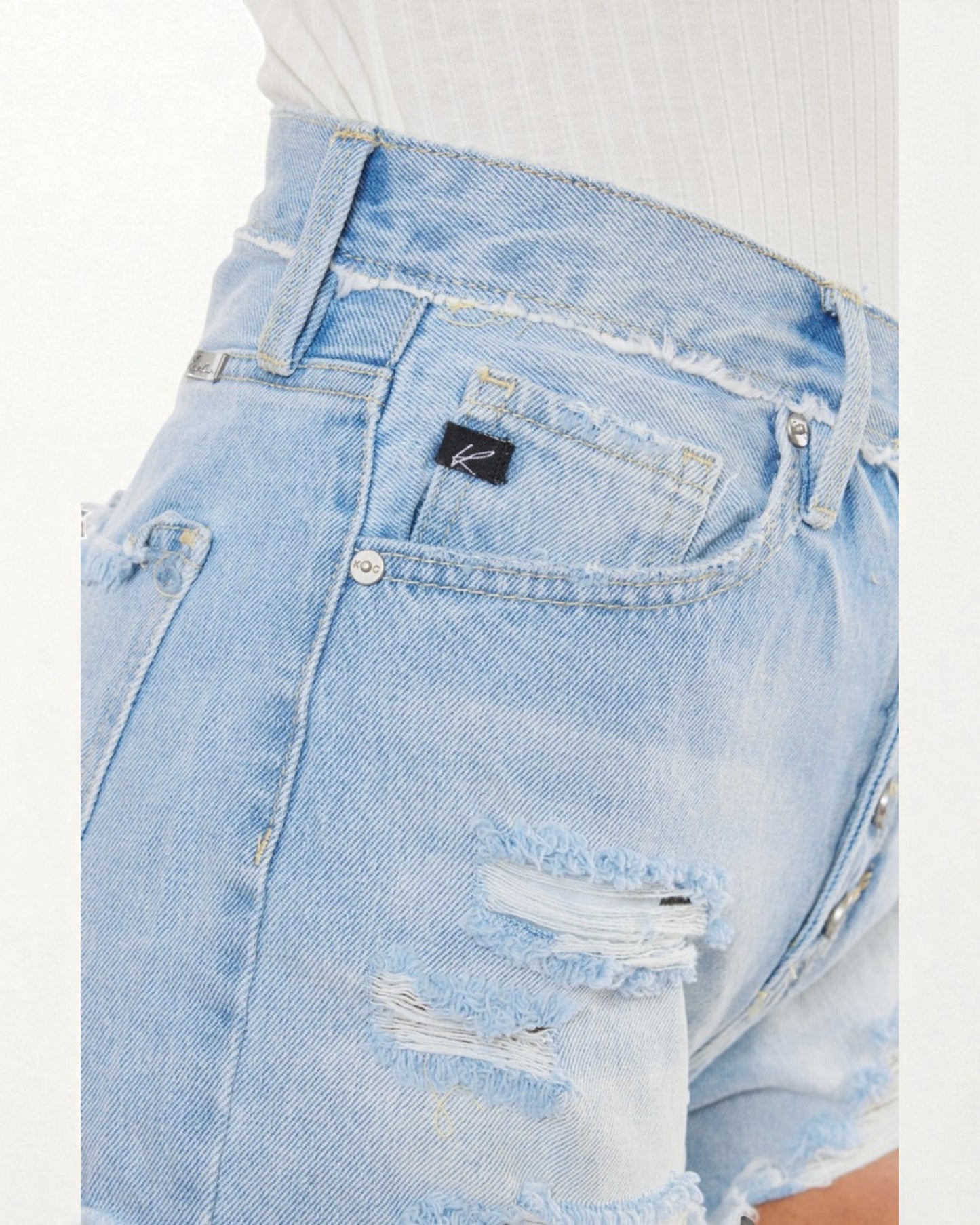 Close-up of light blue denim shorts with a brand logo on a white background