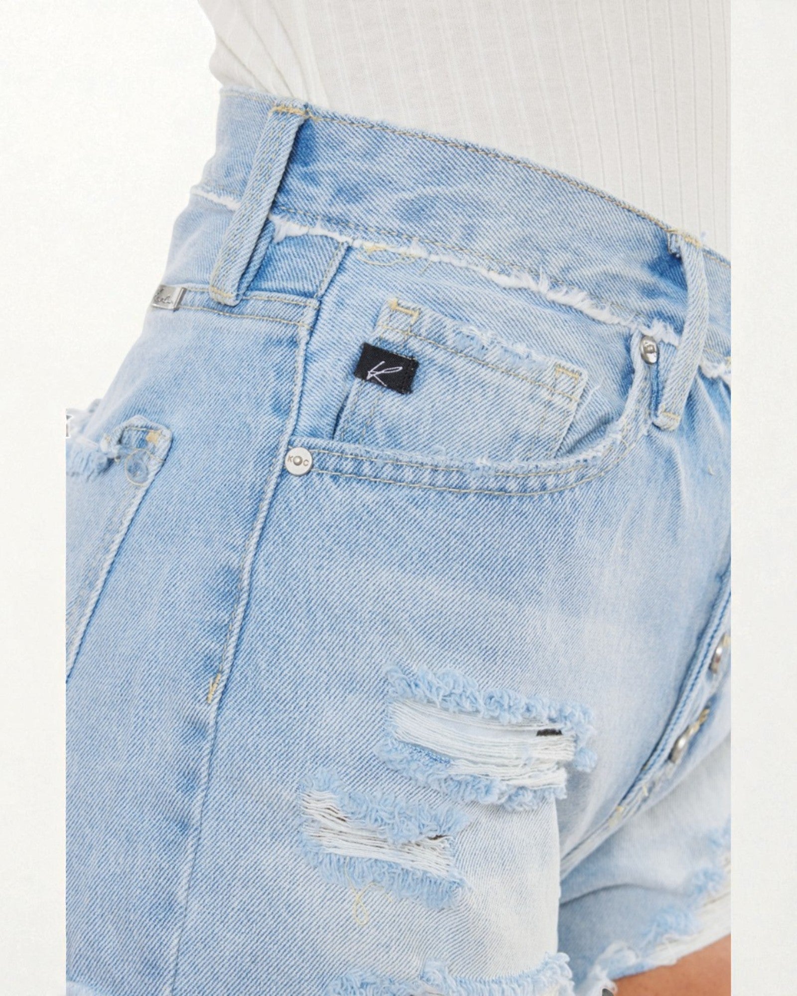 Close-up of light blue denim shorts with a brand logo on a white background