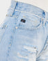 Close-up of light-wash distressed denim jeans showing the back pocket with a black Levi's logo tab, metal rivets, and frayed detailing.