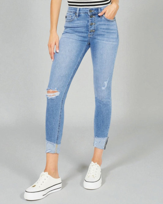 Person wearing light blue distressed jeans on a gray background