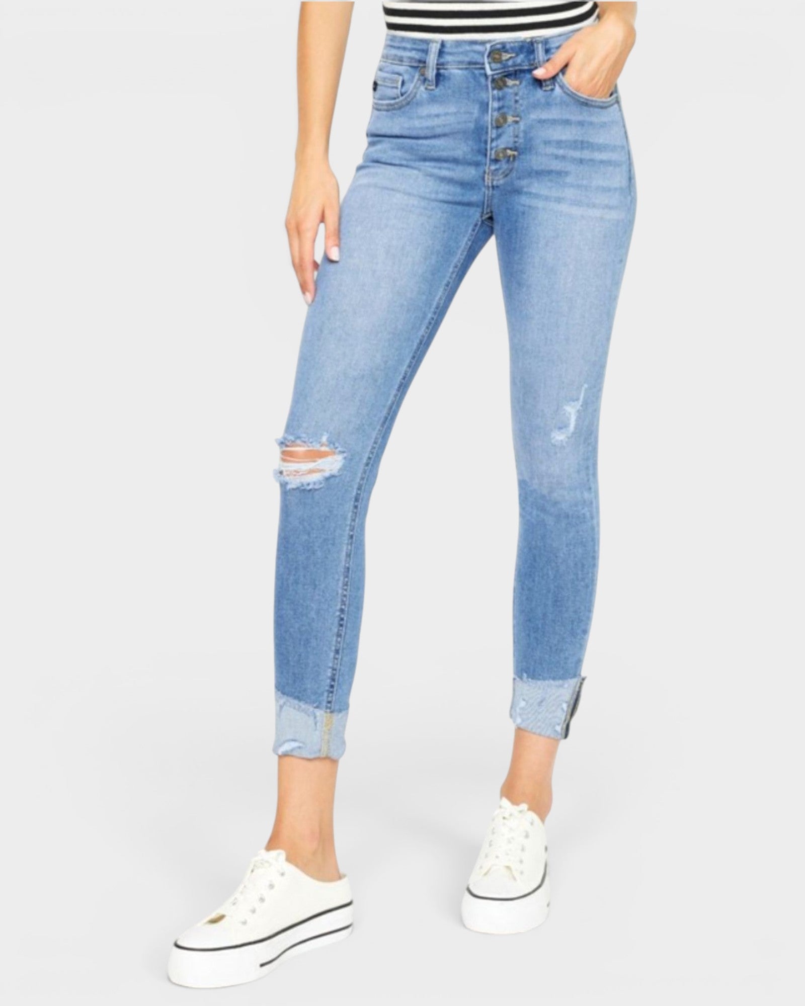 Person wearing light blue distressed jeans on a white background