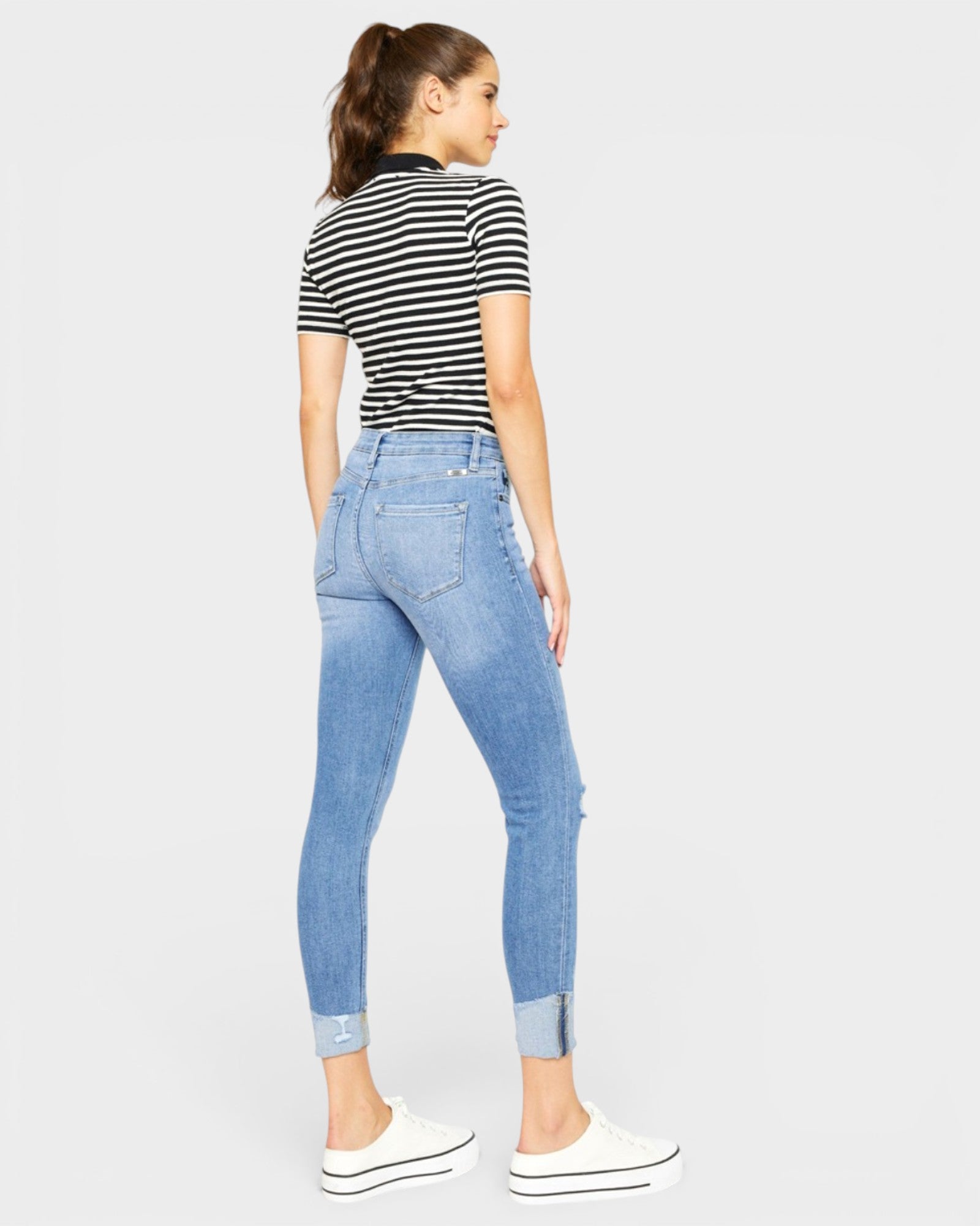 Woman wearing a striped shirt and light blue jeans on a white background