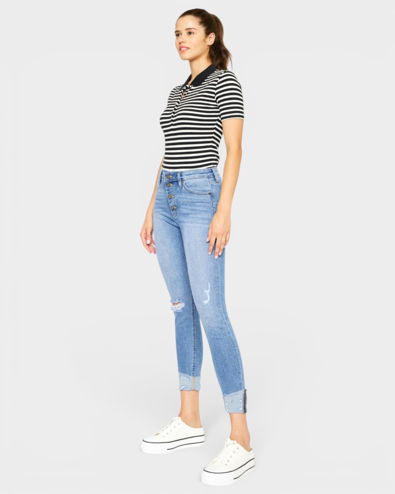Woman wearing a striped shirt and light blue jeans on a white background