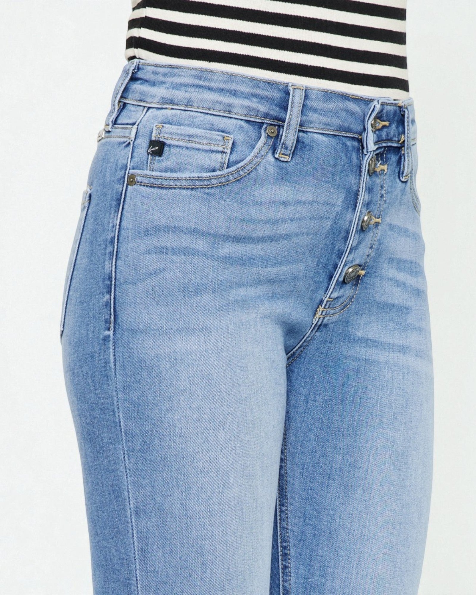 Light blue jeans worn with a black and white striped shirt on a light gray background