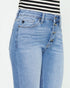 Light blue jeans worn with a black and white striped shirt on a light gray background