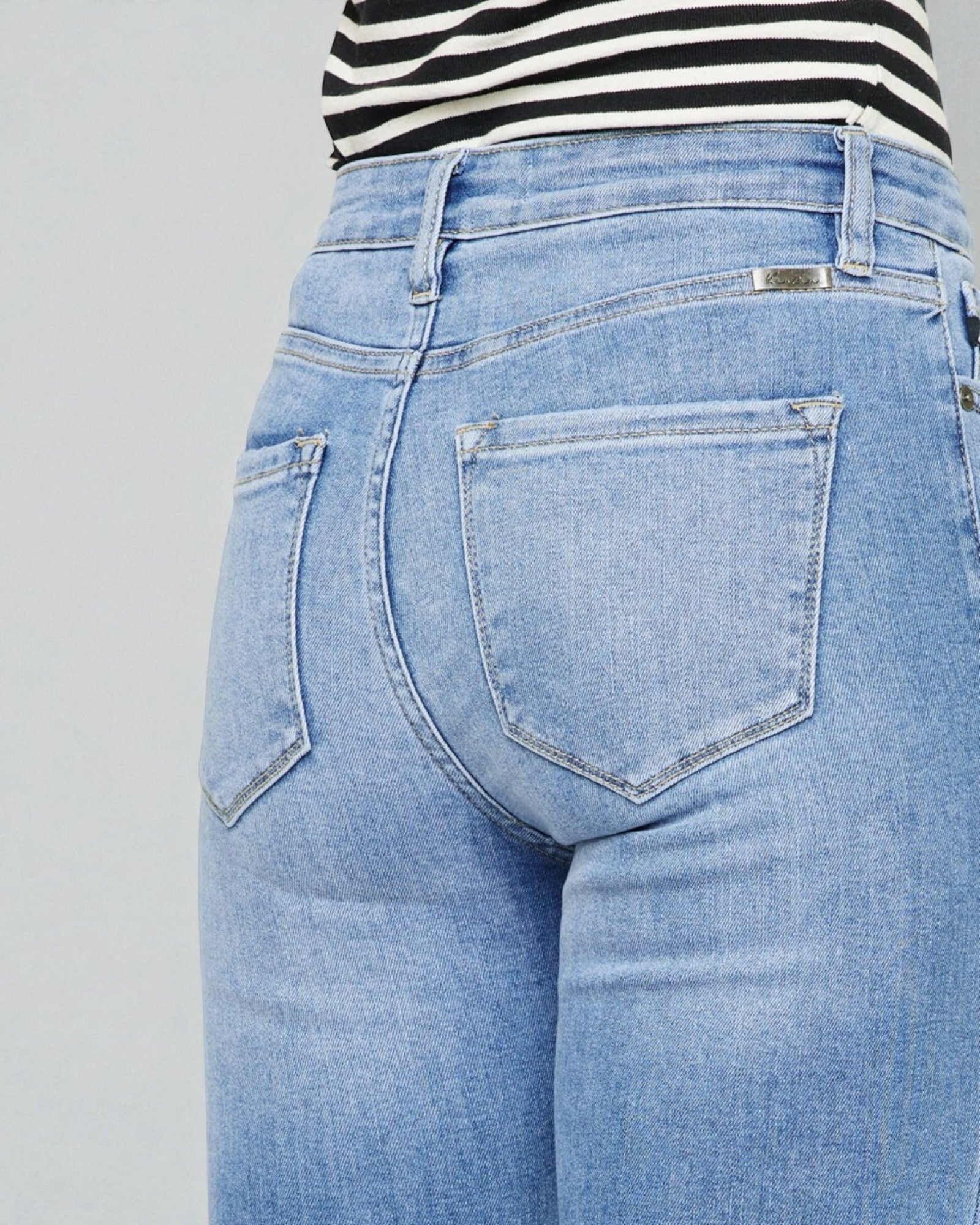 Light blue jeans worn by a person on a gray background