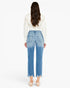A woman viewed from the back wearing light blue cropped jeans with a faded wash, a cream long-sleeve top, and nude heels against a plain white studio background.