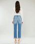 Person wearing blue jeans and a white top on a plain background