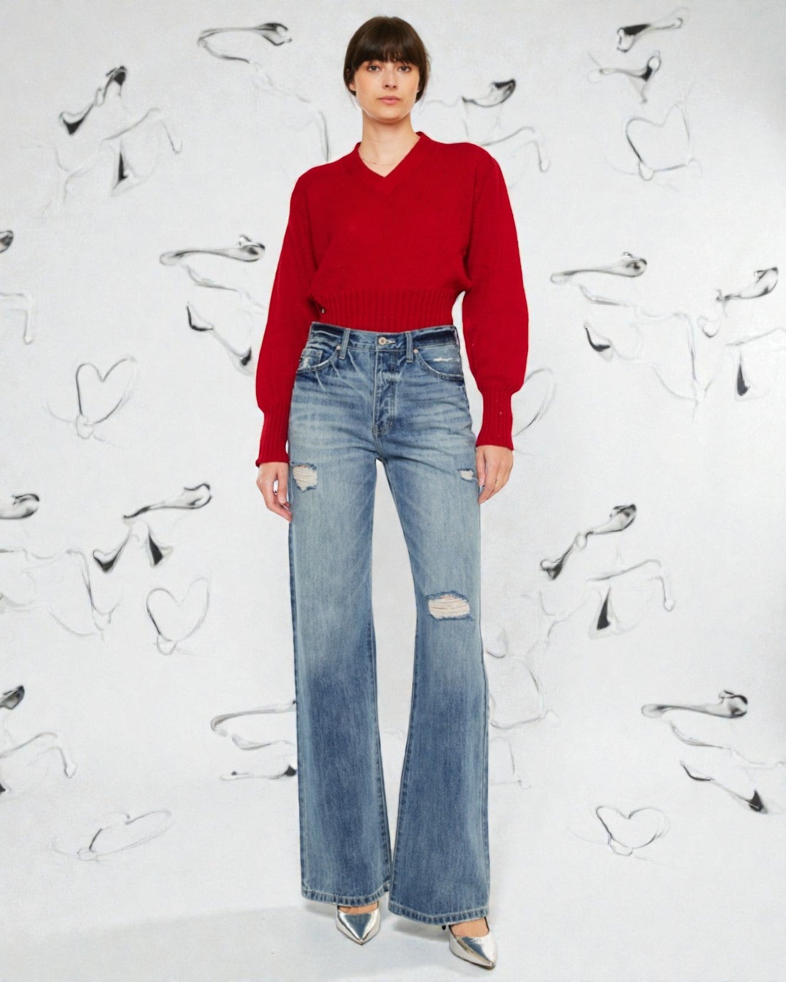 Person wearing a red sweater and blue jeans against a white background with black shoe prints.