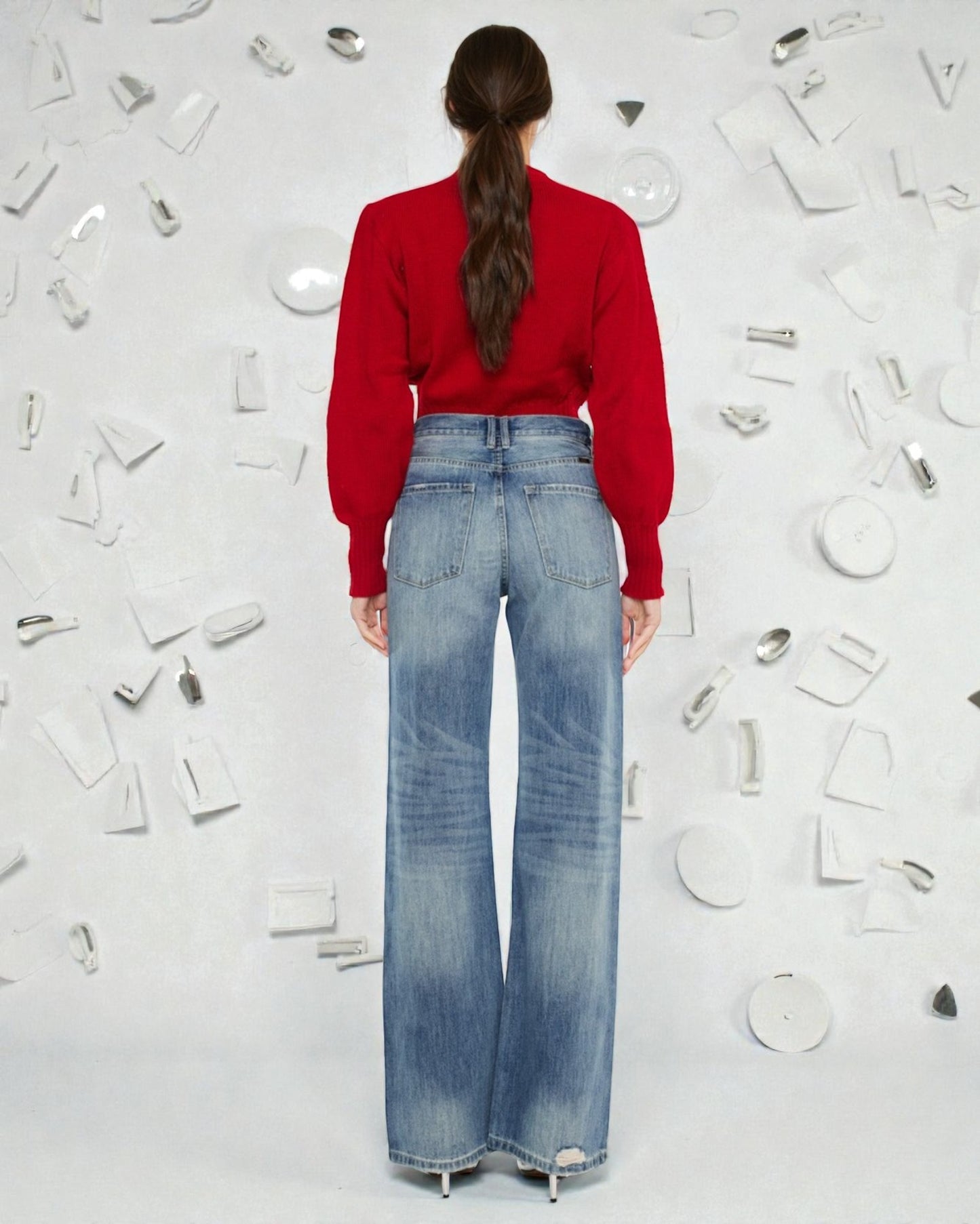 Person wearing a red sweater and blue jeans standing against a white background with decorative elements.