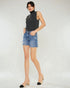 Woman wearing a dark gray sleeveless top and blue denim shorts on a white background
