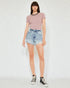 Person wearing a pink ribbed sweater and denim shorts on a white background