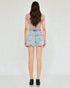 Person wearing a pink top and light blue denim shorts on a white background