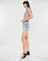 Woman wearing a pink top and denim shorts on a white background