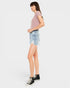A woman modeling a light pink short-sleeve knit top, light-wash denim cargo shorts, and black high-top sneakers against a plain light gray studio background.