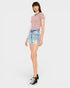 A model wearing a dusty pink short-sleeve knit top, light-wash denim shorts, and black high-top sneakers, standing against a solid light gray background.
