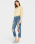 Woman wearing a yellow sweater and distressed blue jeans on a white background