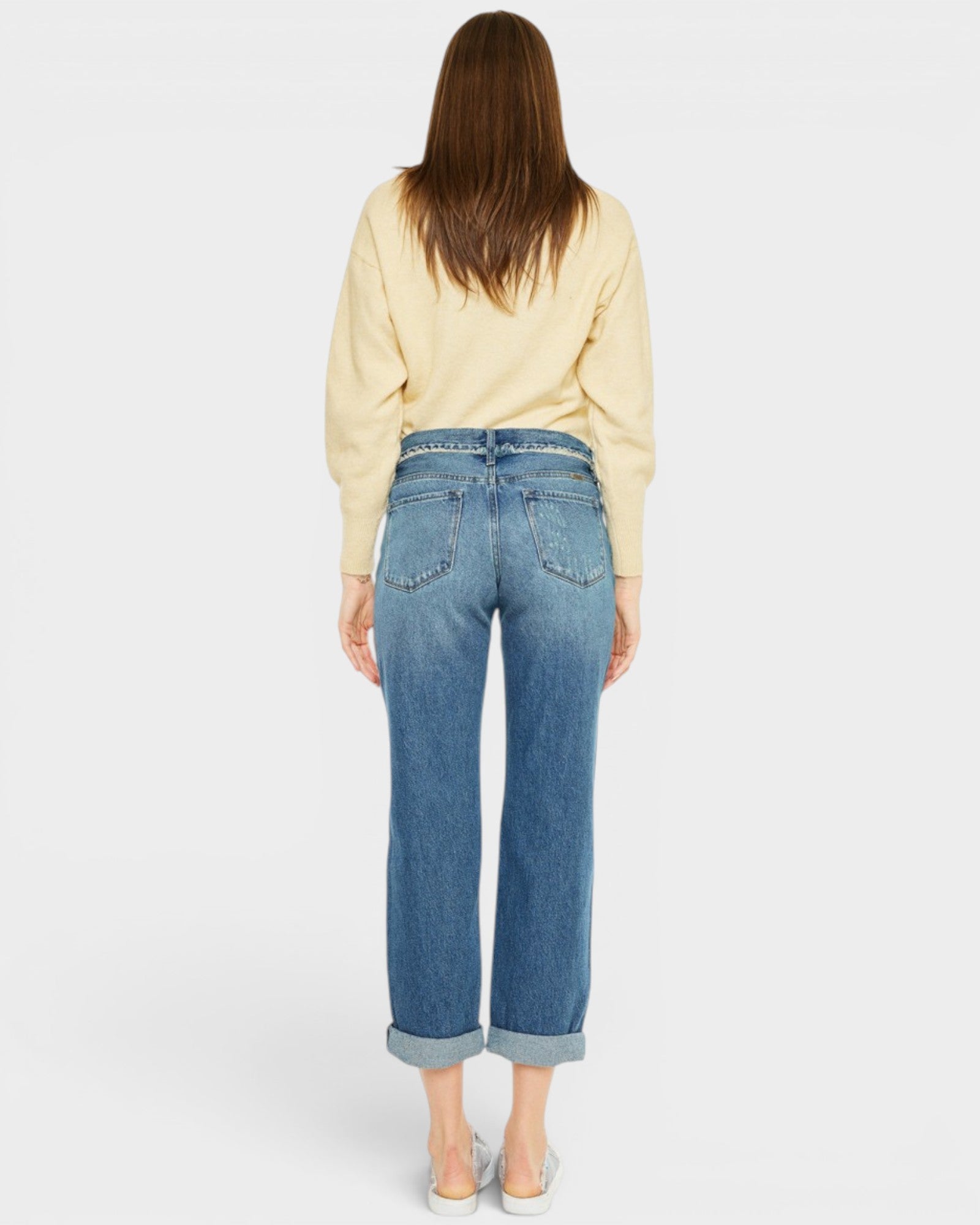 Person wearing blue jeans and a light-colored top on a plain background