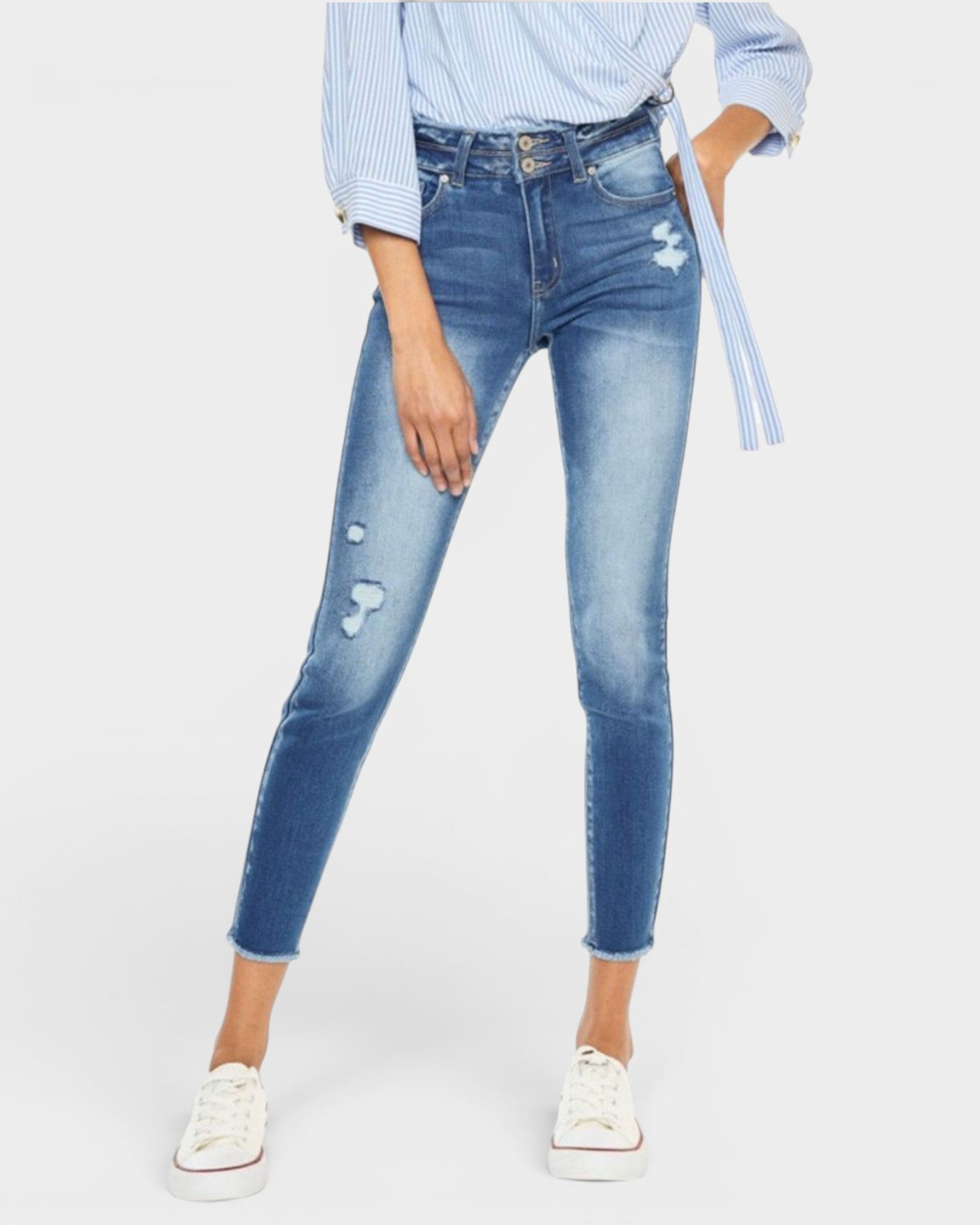 Person wearing blue distressed jeans on a white background