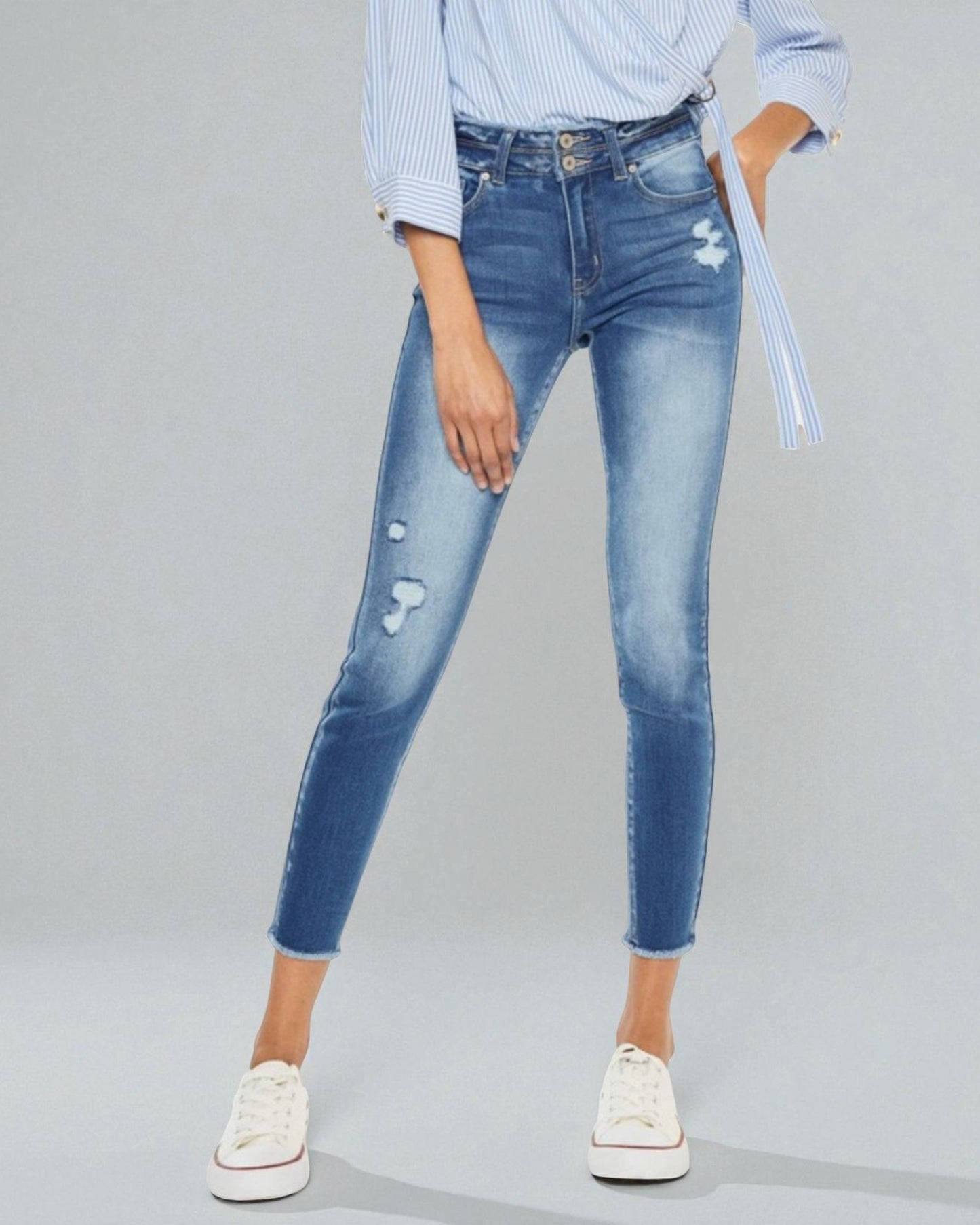 Person wearing blue jeans and a light blue shirt on a gray background