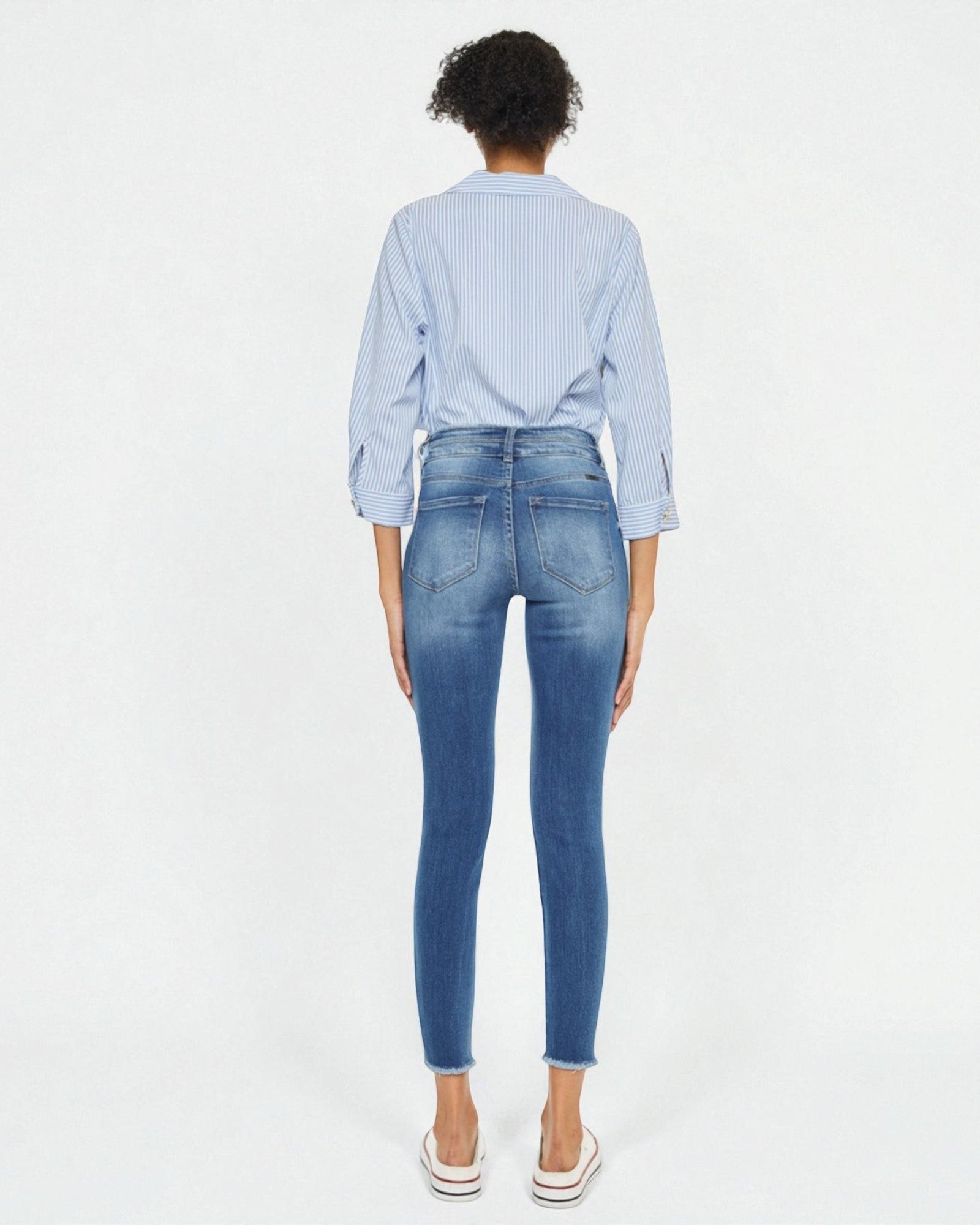 Person wearing blue jeans and a light blue checkered shirt on a white background