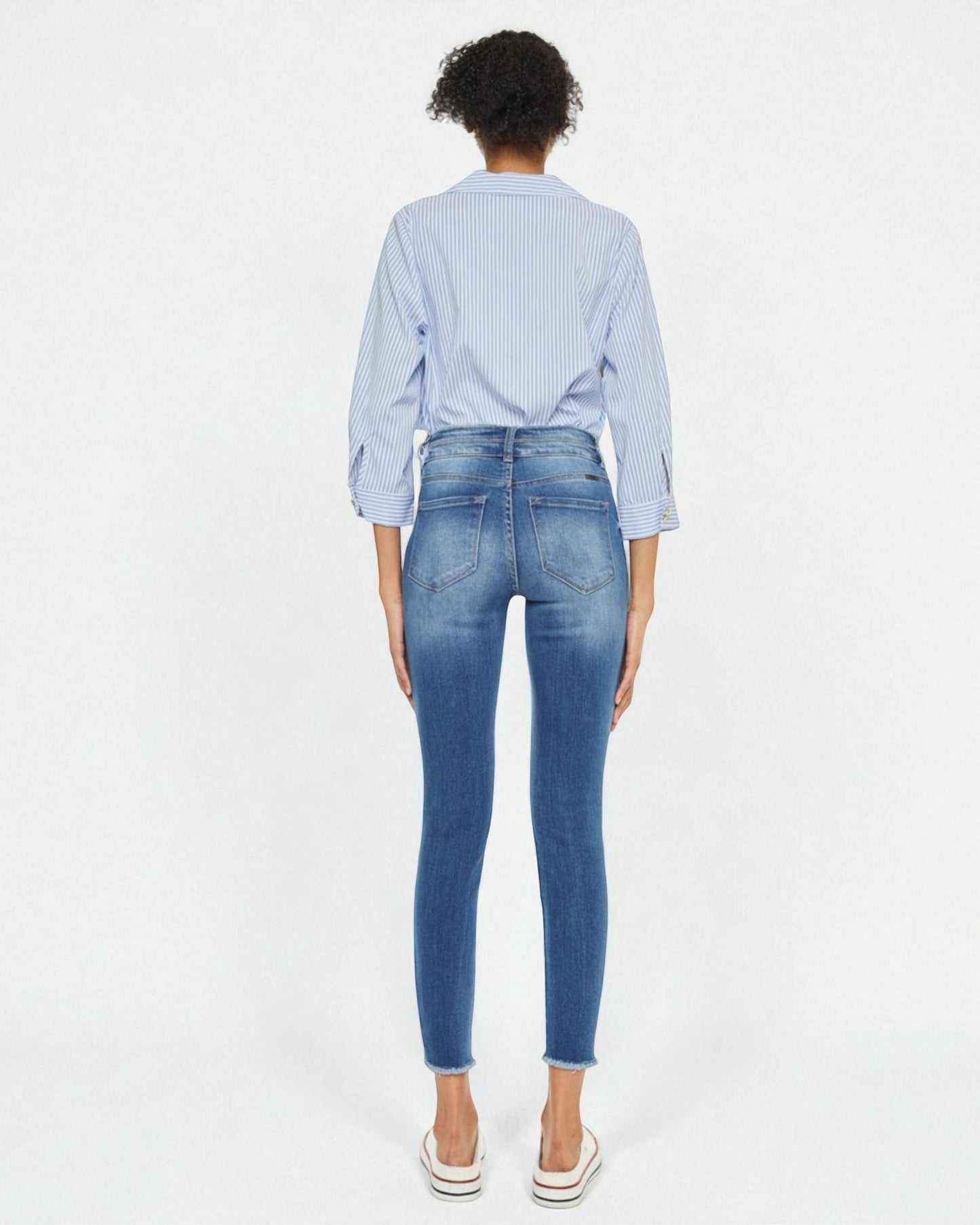 Person wearing blue jeans and a light blue checkered shirt on a white background