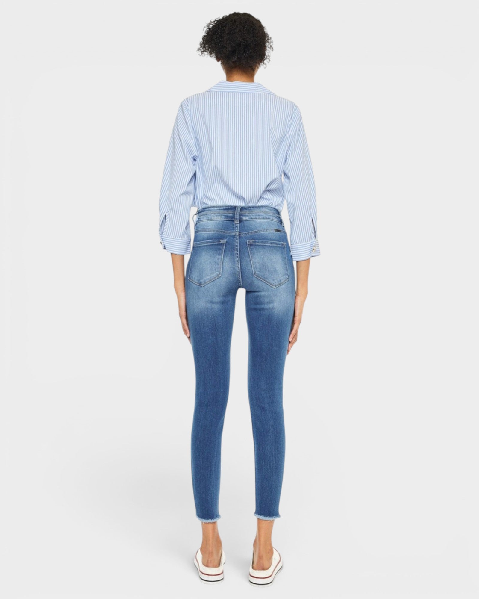 Person wearing blue jeans and a light blue checkered shirt on a white background