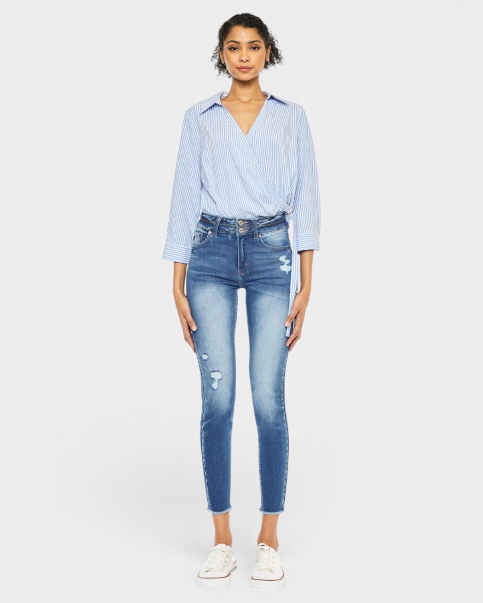 Woman wearing a light blue striped shirt and jeans on a white background