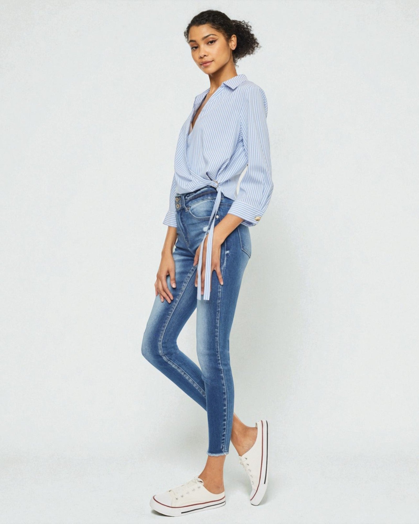 Woman wearing a light blue shirt and jeans on a white background