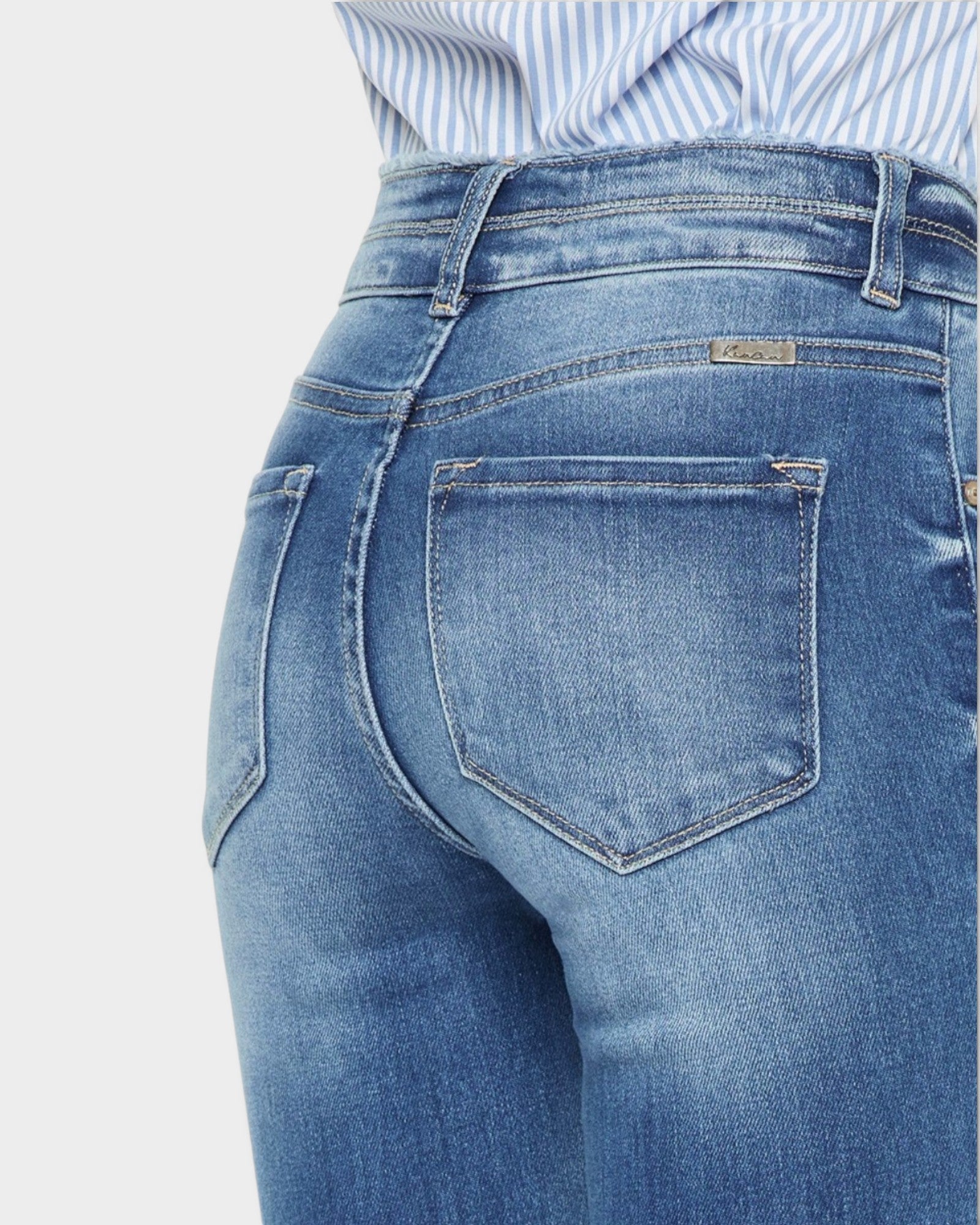 Close-up of blue jeans with a brand label on a light gray background