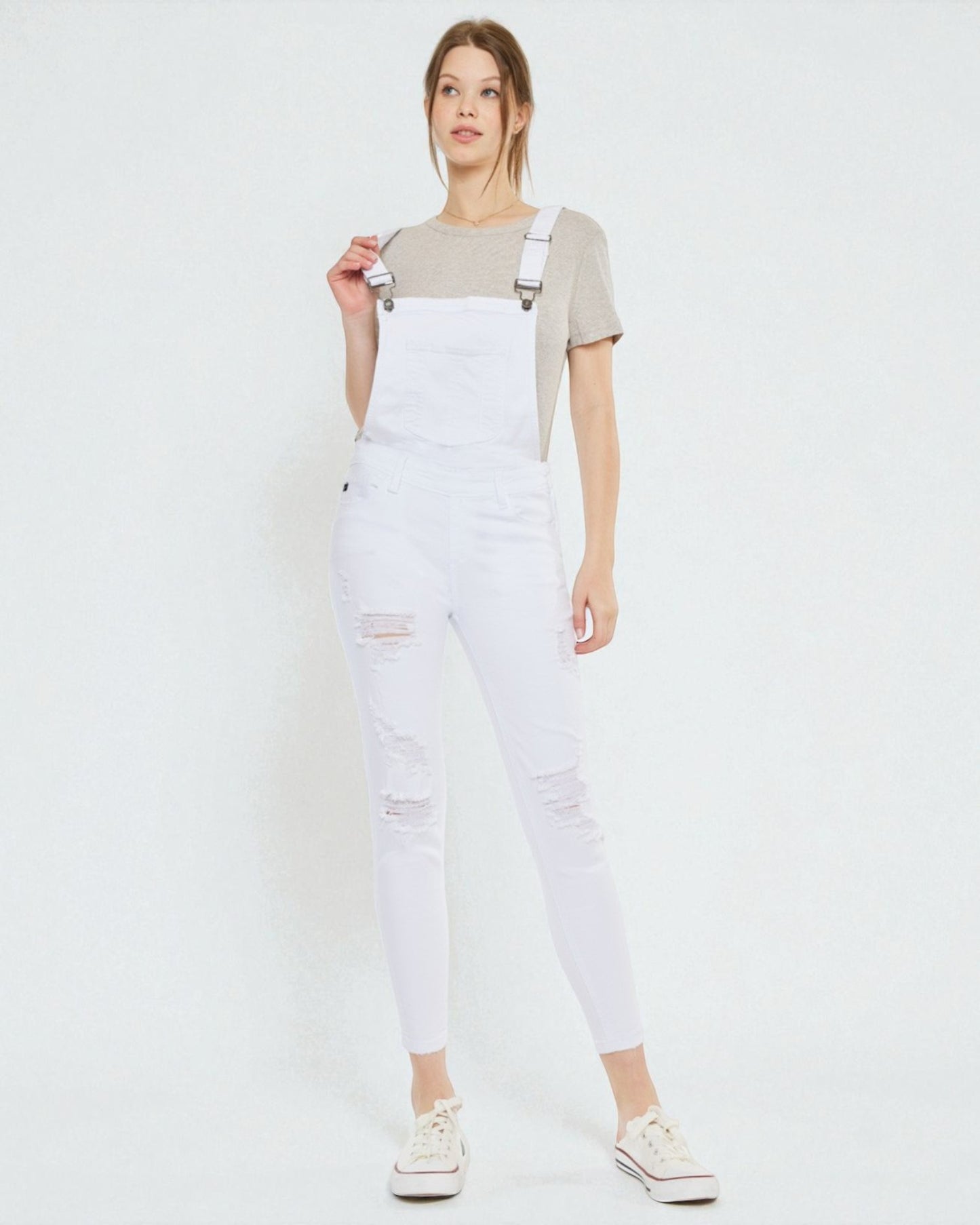 Person wearing white denim overalls on a plain background