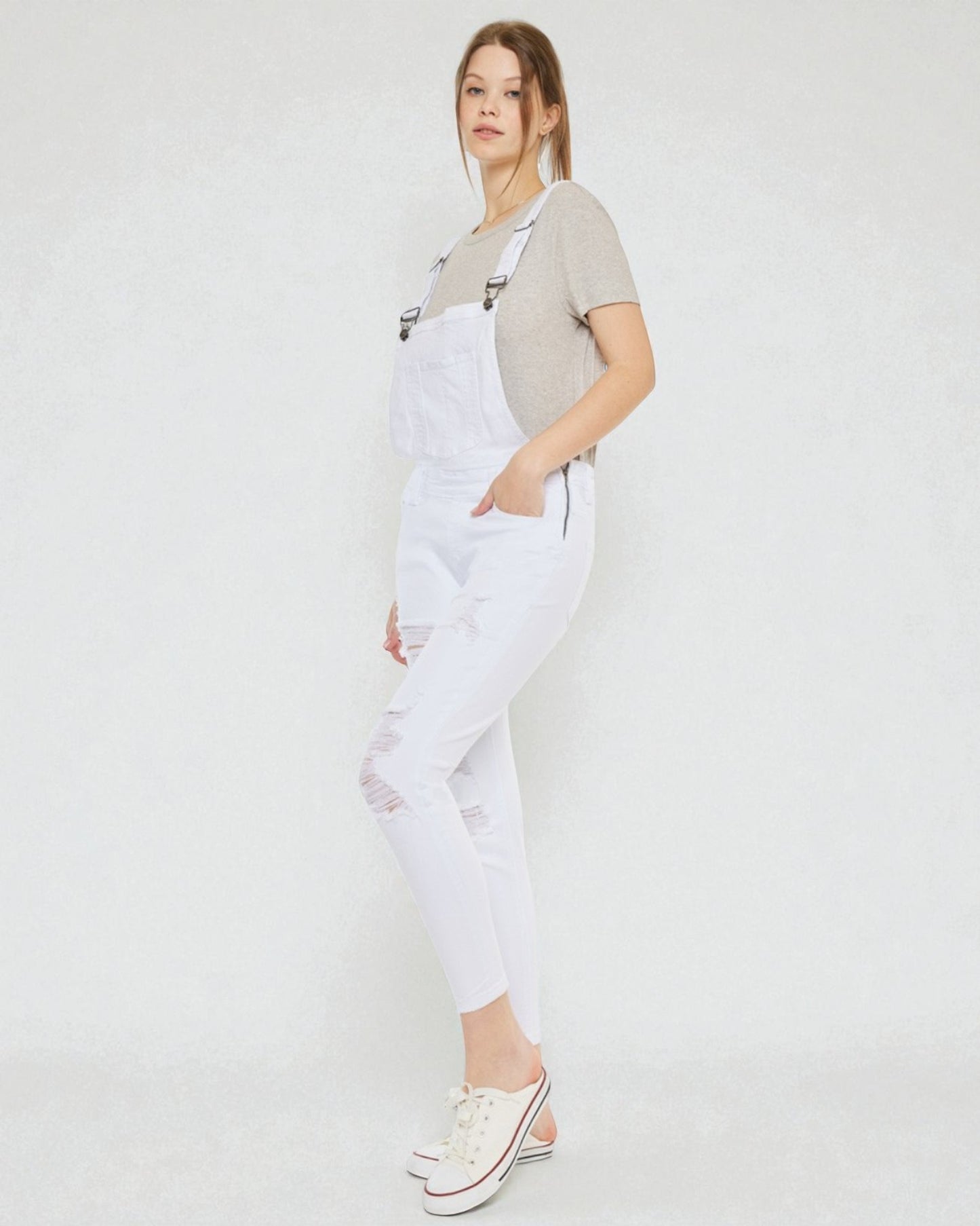 Person wearing white overalls on a plain background