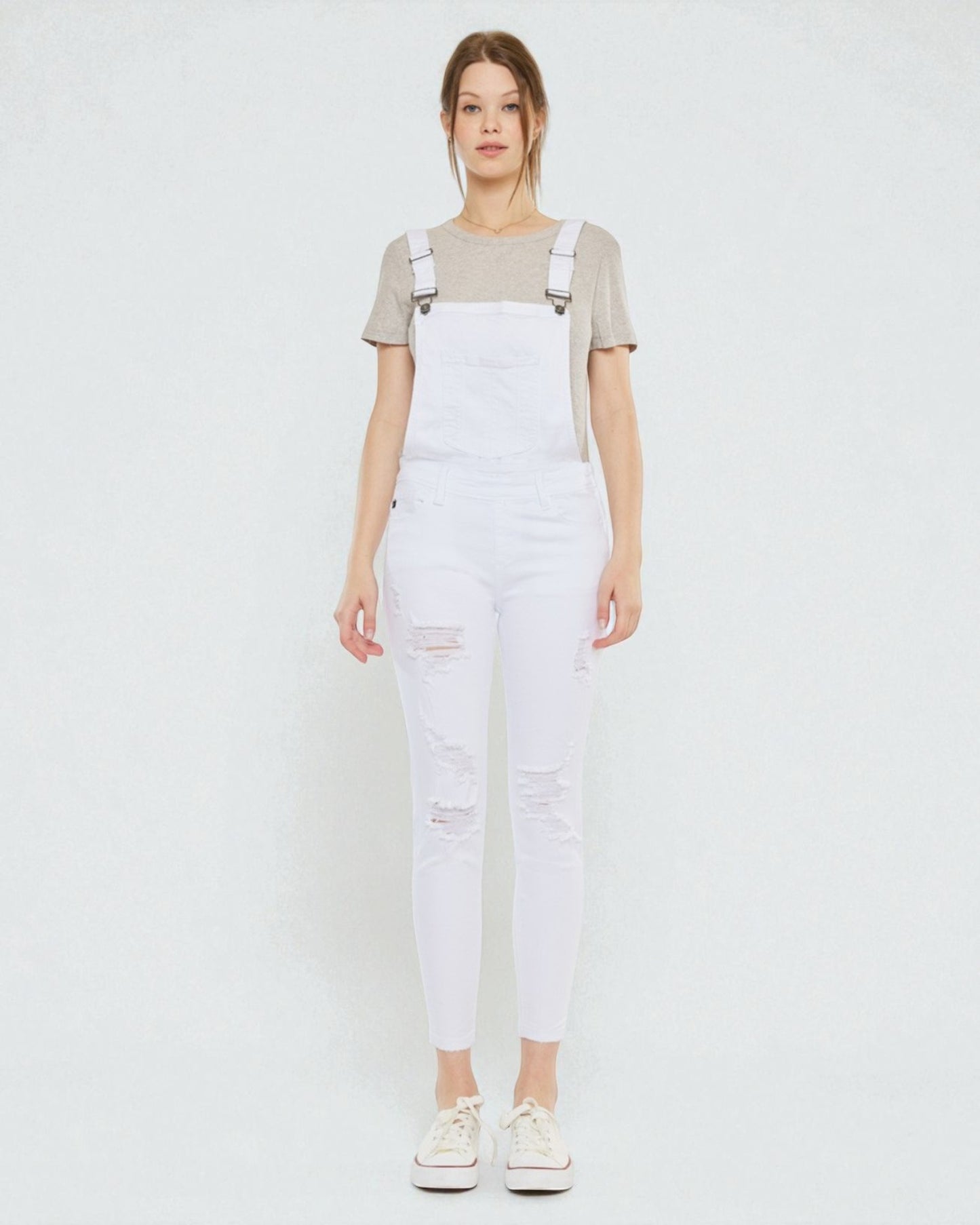 Person wearing white denim overalls on a plain background
