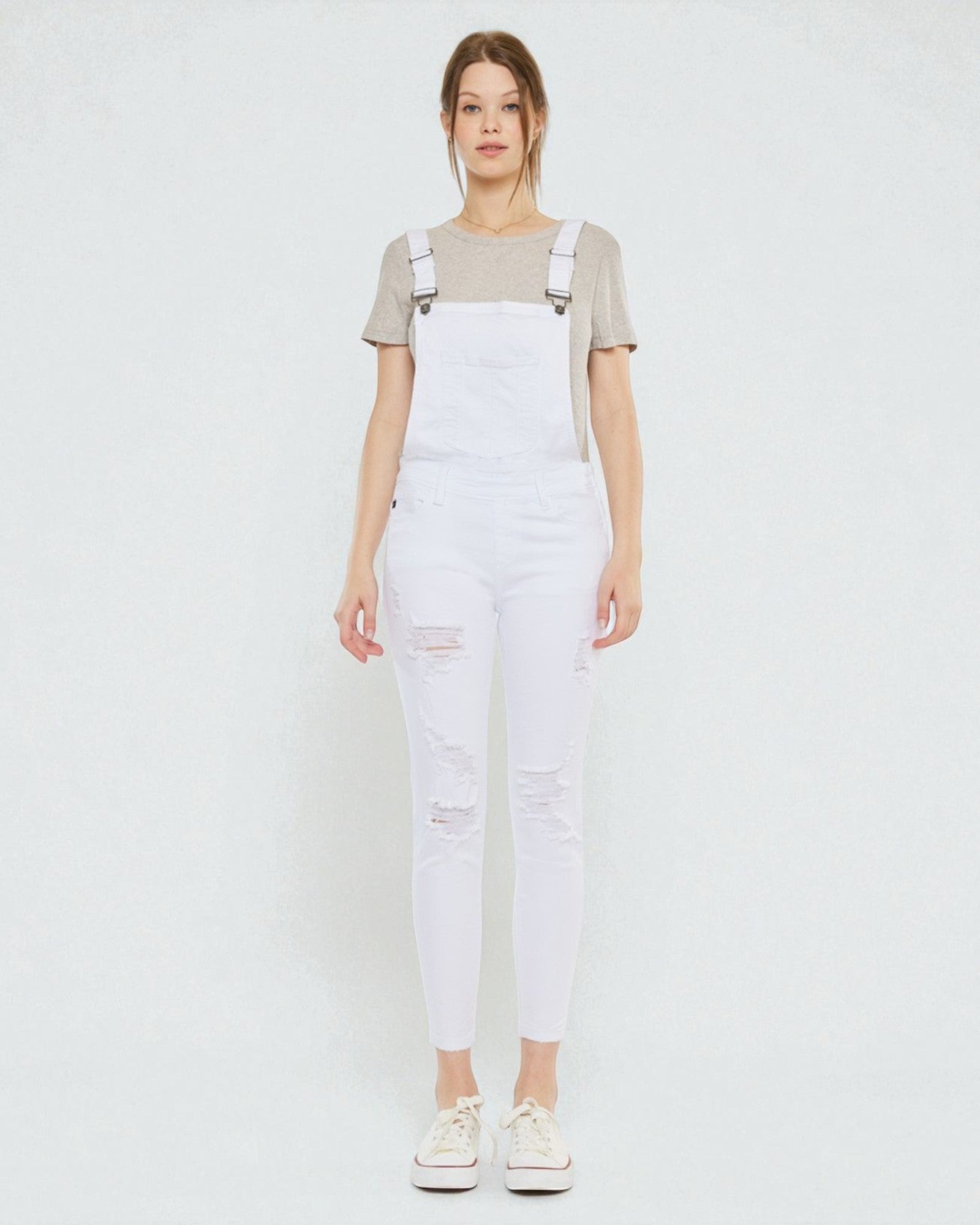 Person wearing white denim overalls on a plain background