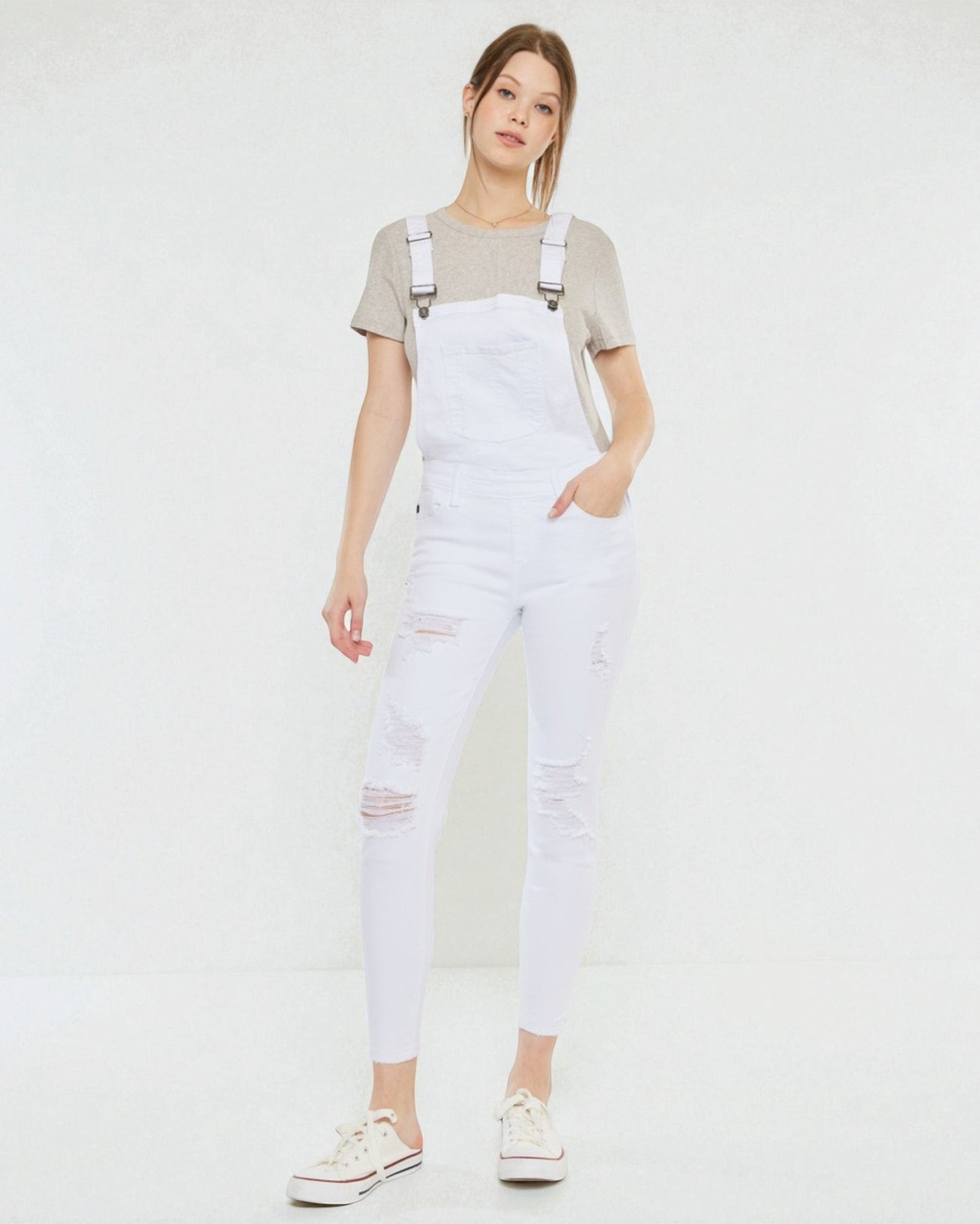 Person wearing white overalls with a plain background