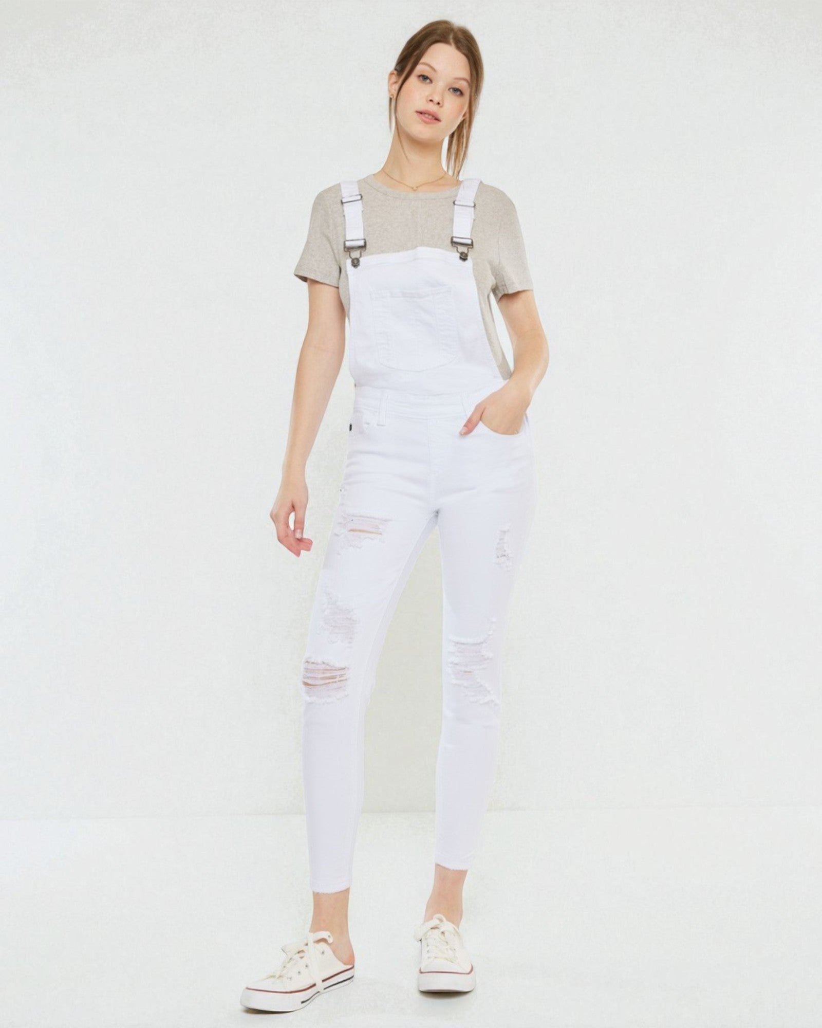Person wearing white overalls with a plain background