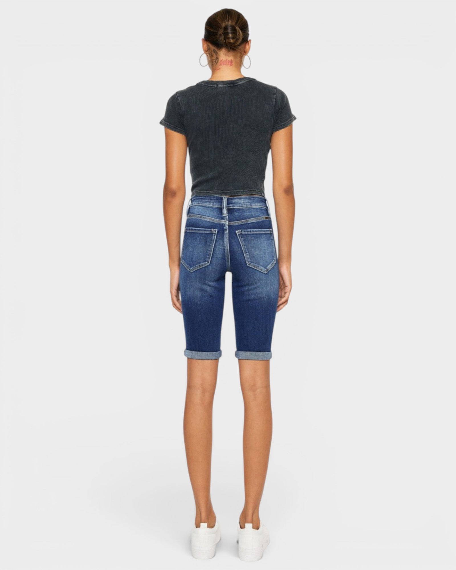 Person wearing blue denim shorts and a black t-shirt on a white background