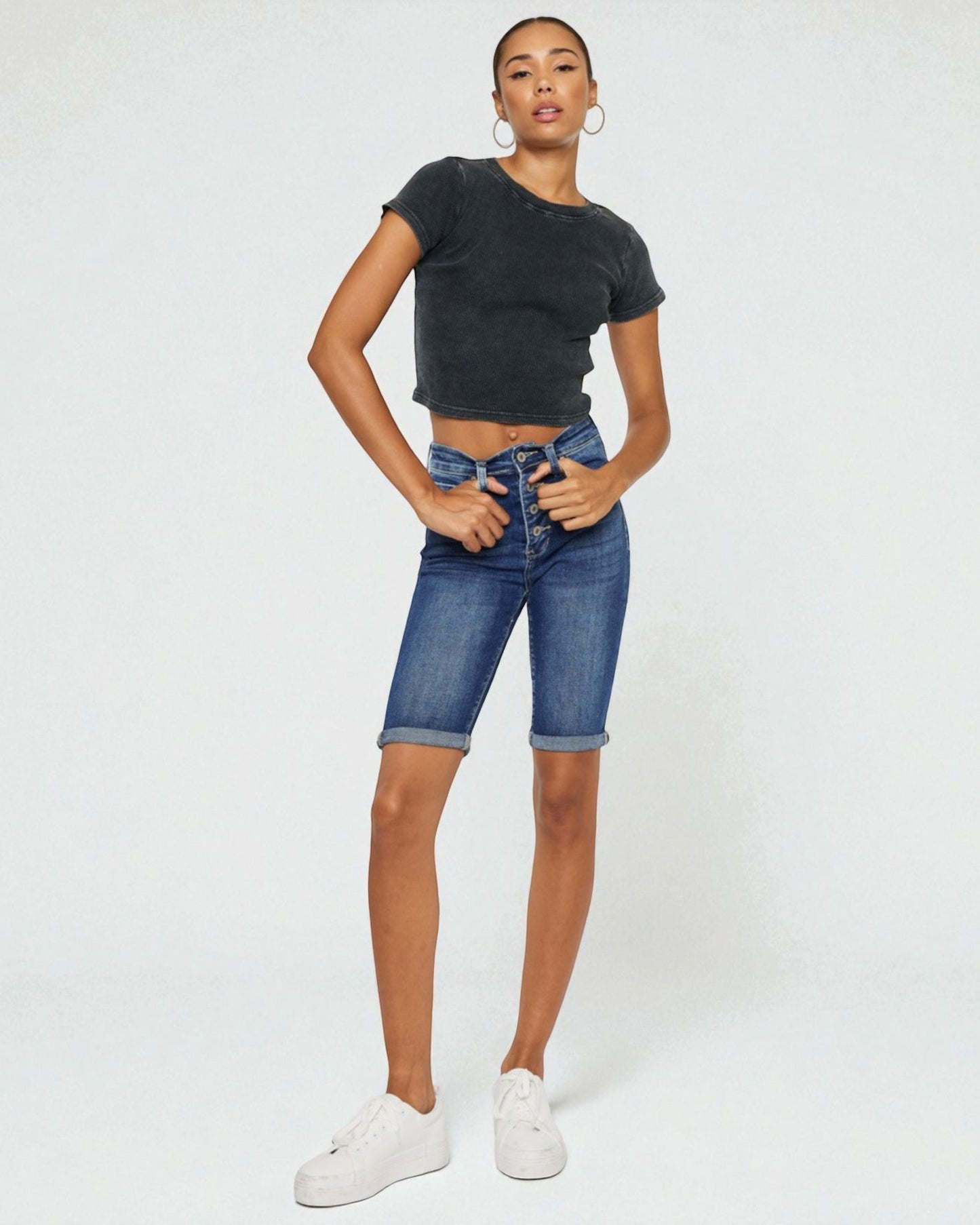 Person wearing a black t-shirt and blue denim shorts on a white background