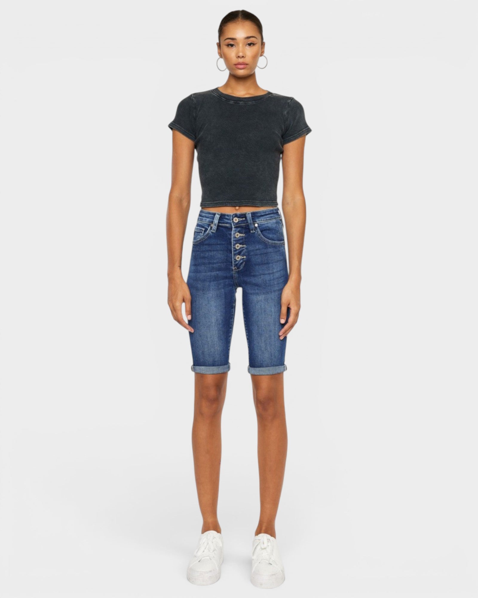 Person wearing a black t-shirt and blue denim shorts on a white background