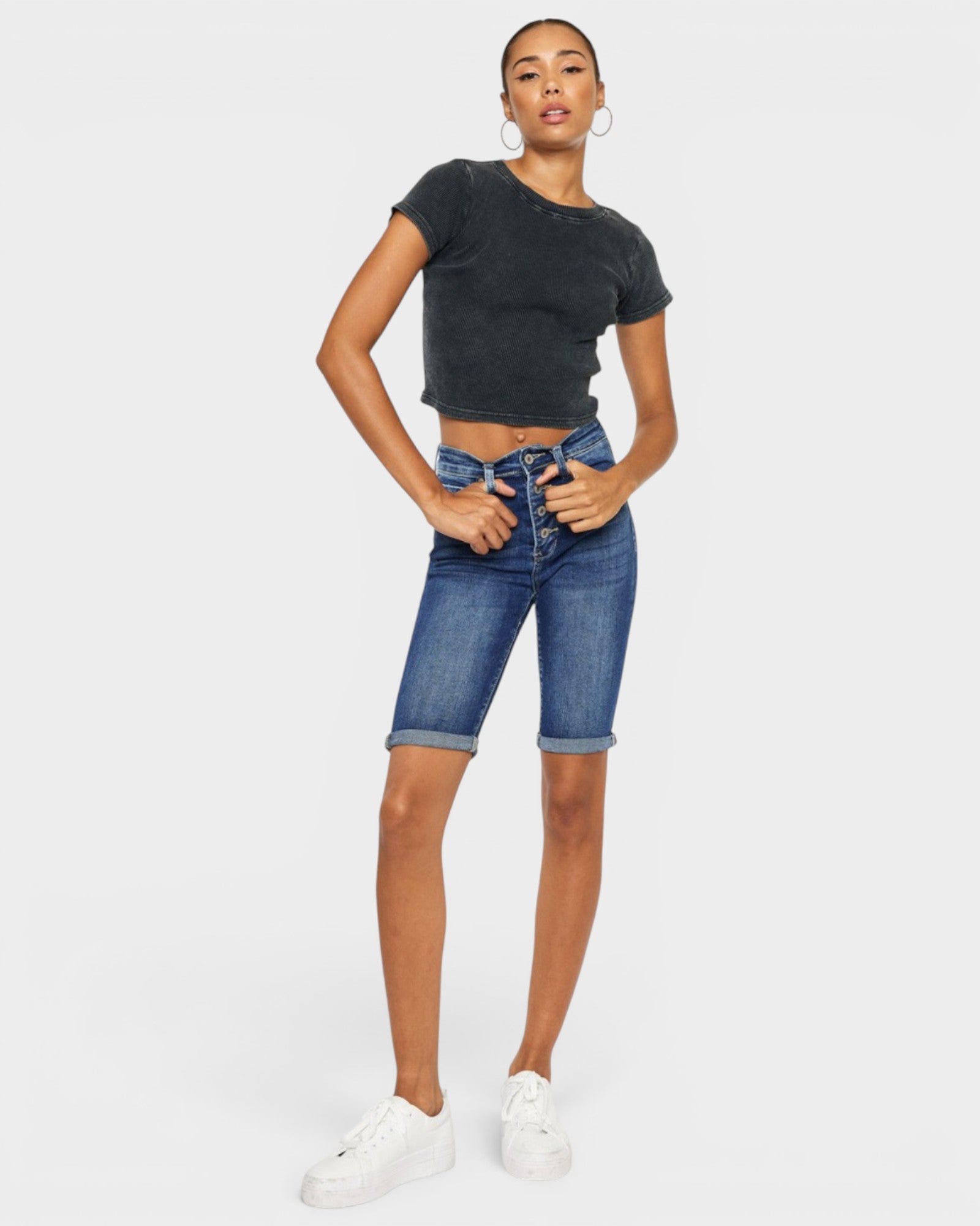 Person wearing a black t-shirt and blue denim shorts on a white background
