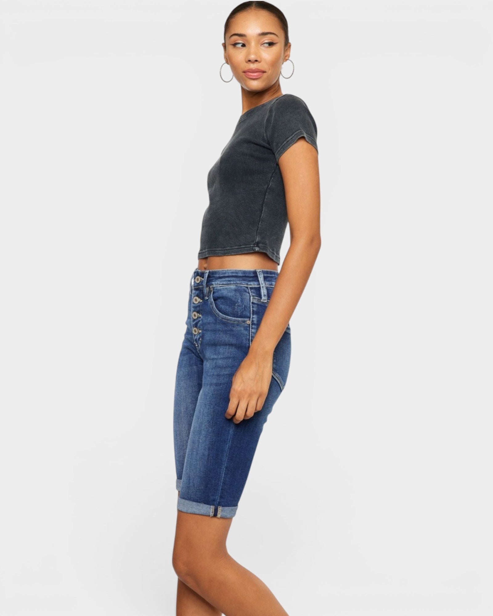 Woman wearing a dark gray cropped t-shirt and blue denim shorts on a white background