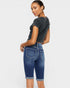Woman wearing a dark gray t-shirt and blue denim shorts on a white background