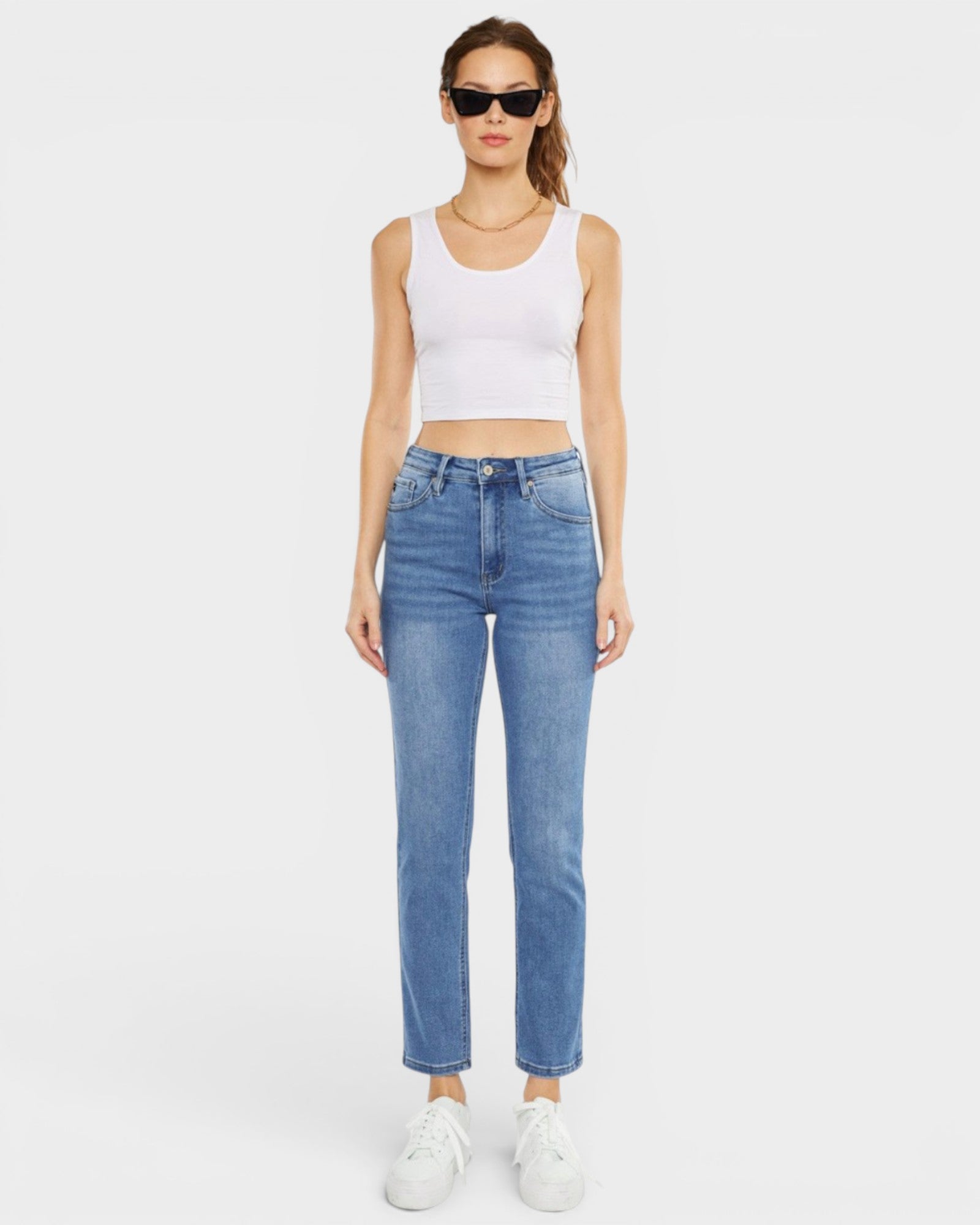 Woman wearing a white tank top and blue jeans on a white background