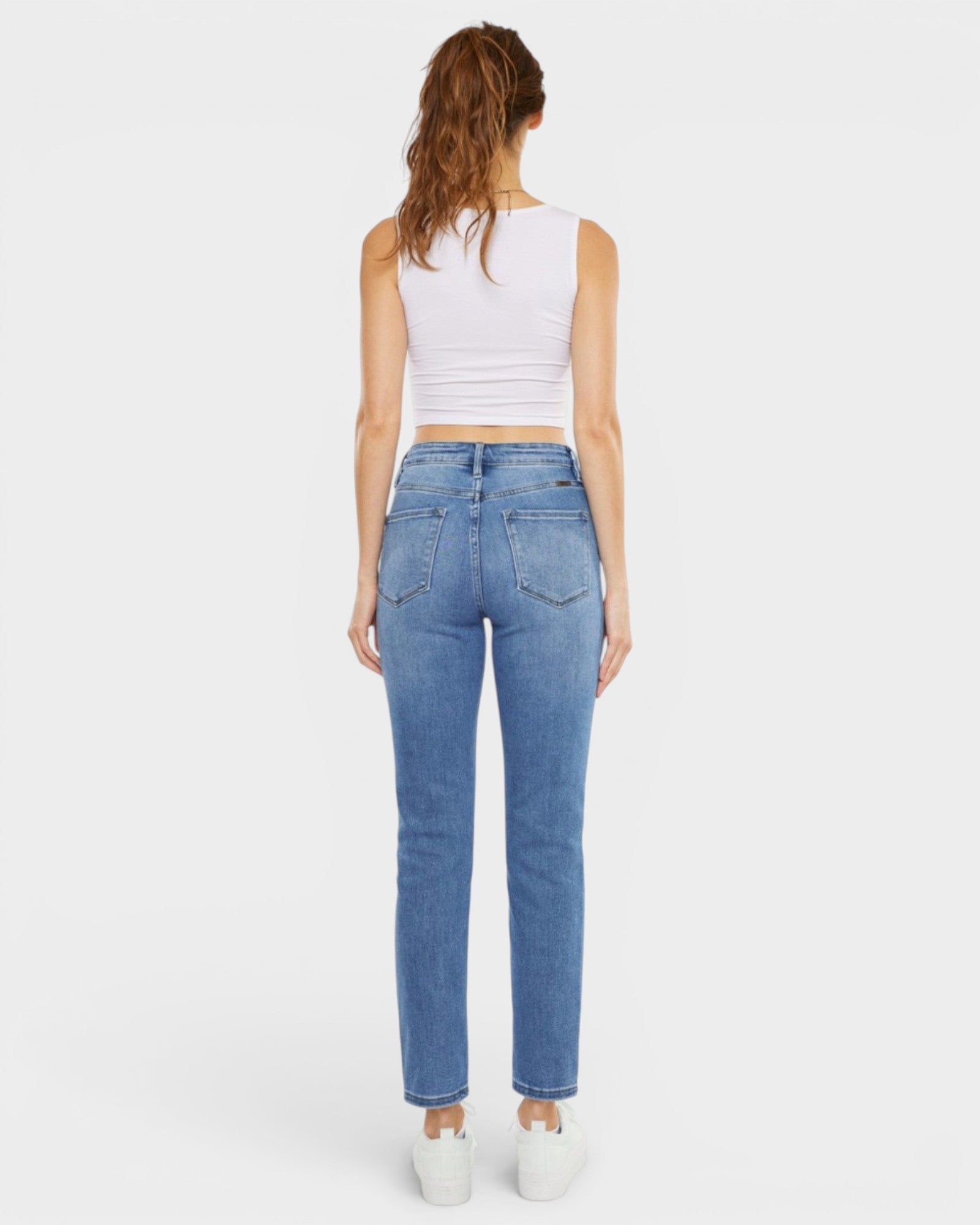 Woman wearing blue jeans and a white top on a white background