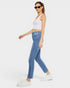 Woman wearing a white tank top and blue jeans on a white background